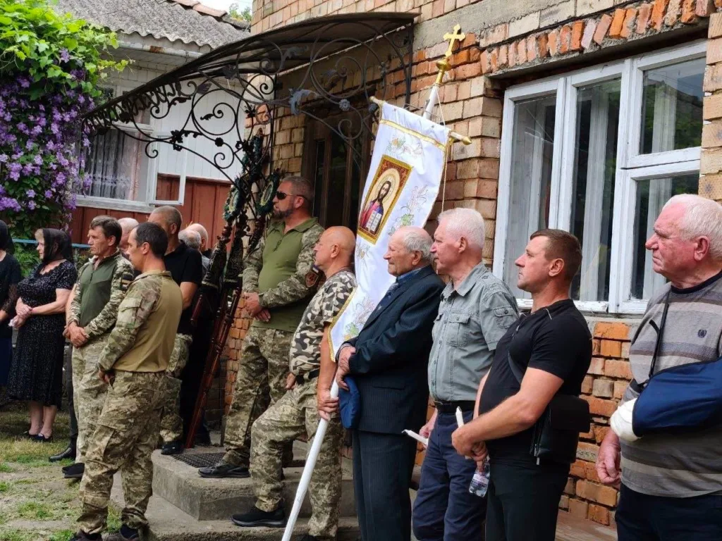 Люди стоять біля будівлі під час церемонії