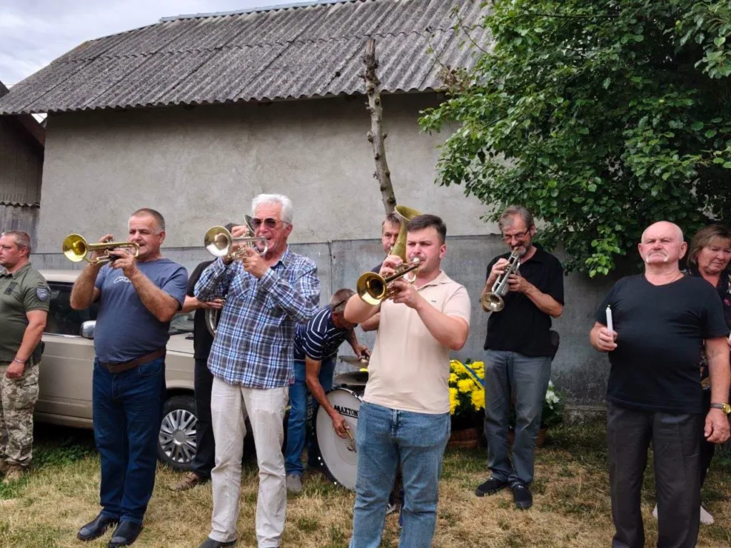 Люди грають на трубах на вулиці біля будинку