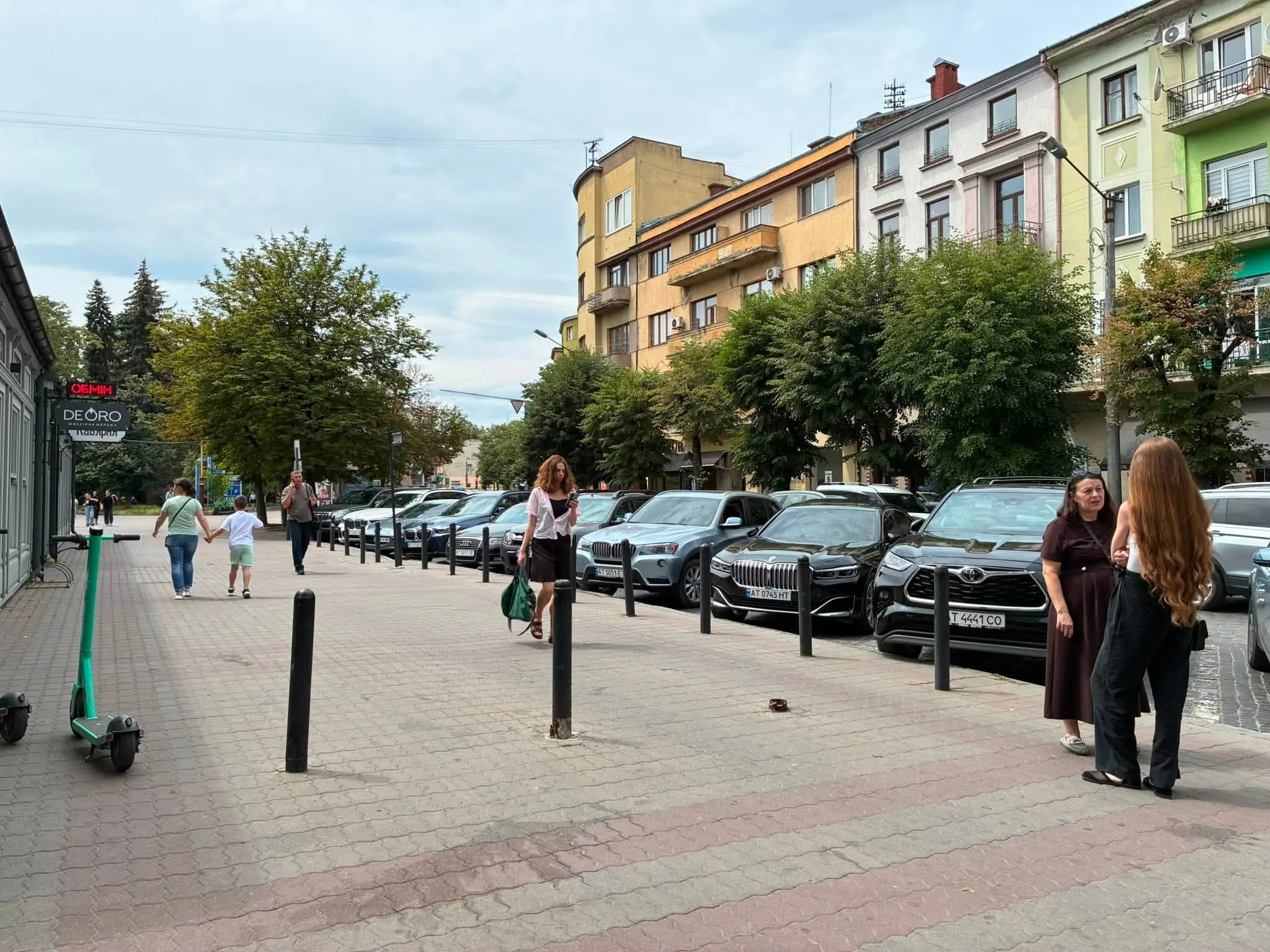 Люди на вулиці біля кольорових будинків і автівок