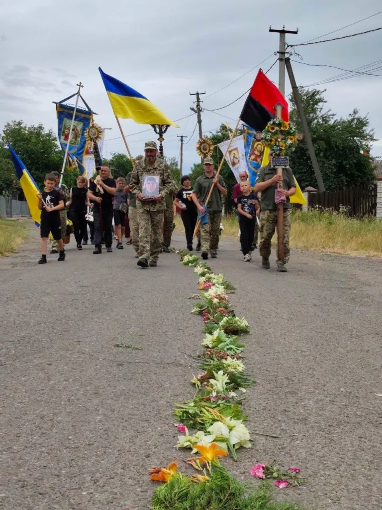 Процесія з українськими прапорами та квітами на дорозі