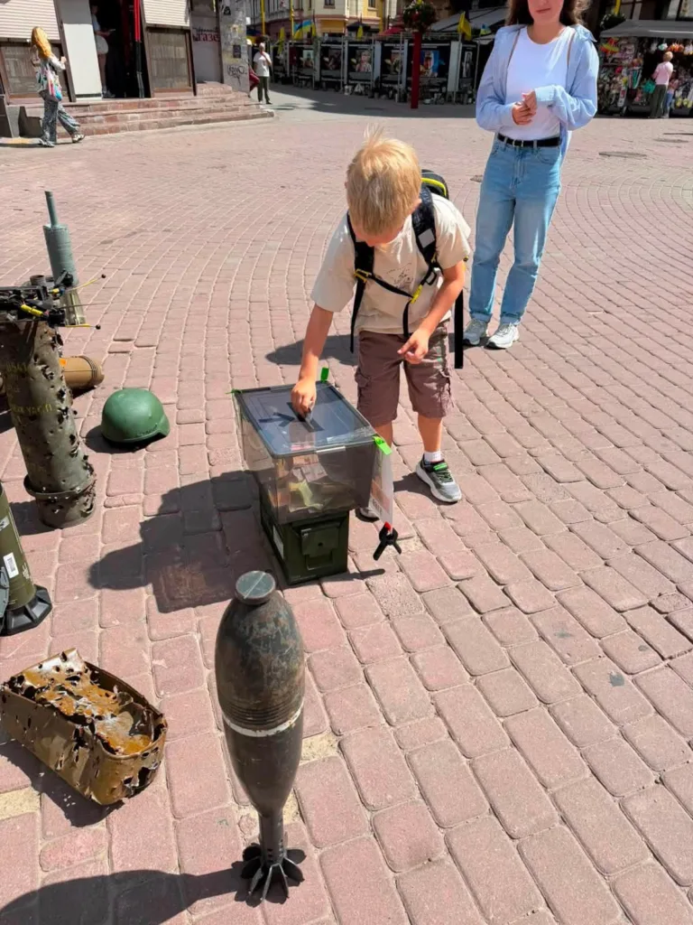 Хлопчик кладе монету у скриньку на вулиці