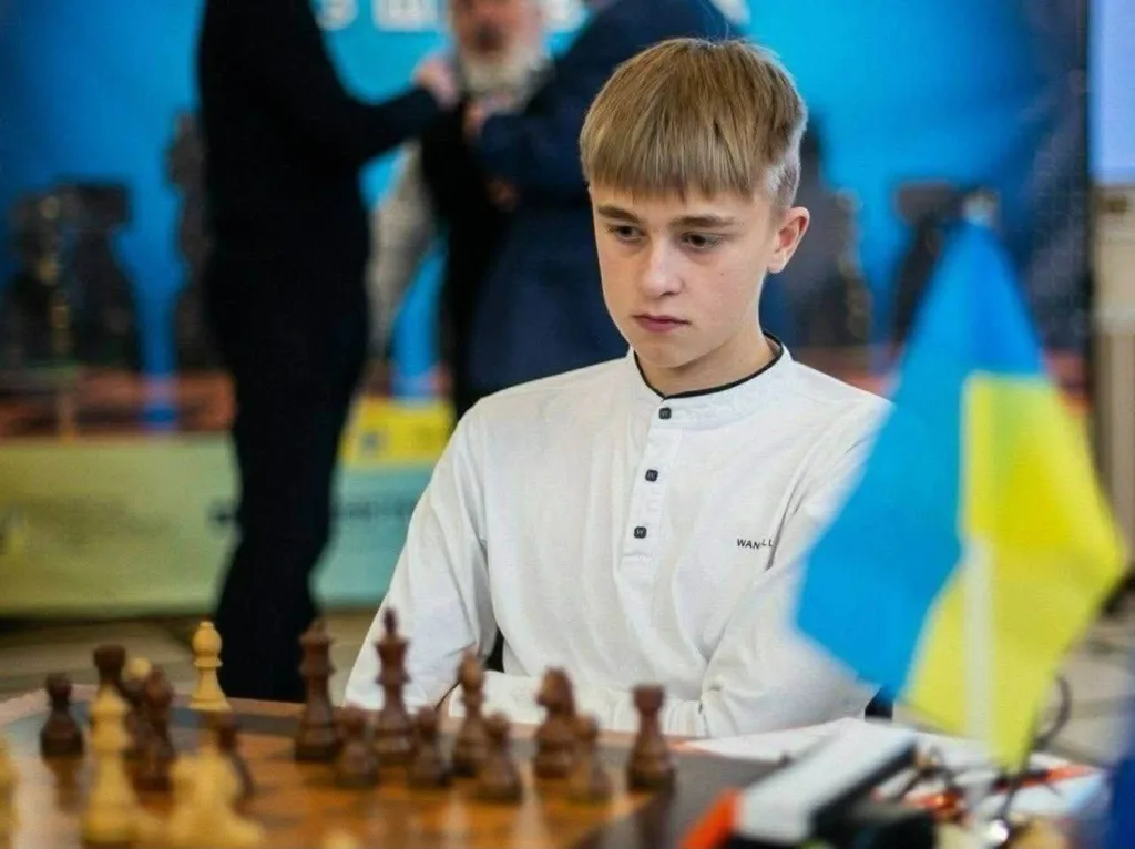 Хлопець грає в шахи з українським прапором