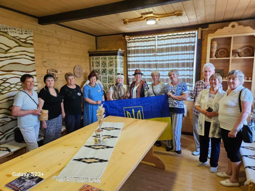 Група людей з українським прапором у дерев’яній кімнаті