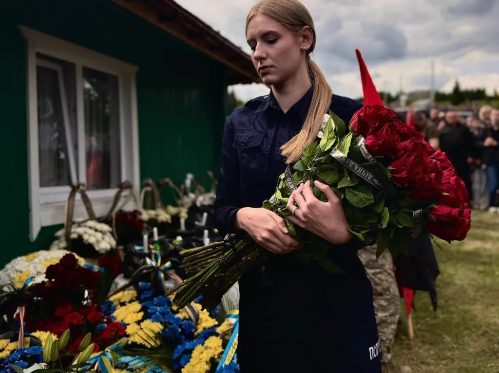 Жінка з букетом червоних троянд на похороні