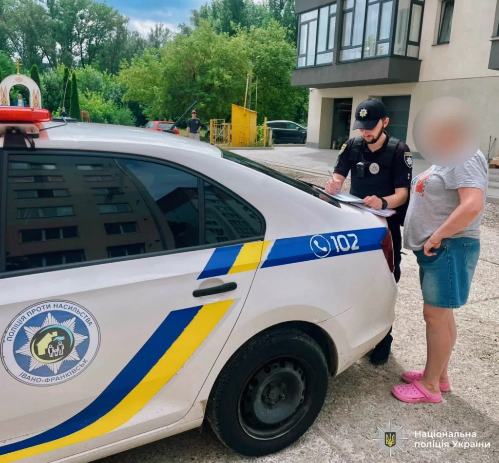 Поліцейський пише звіт біля патрульного авто