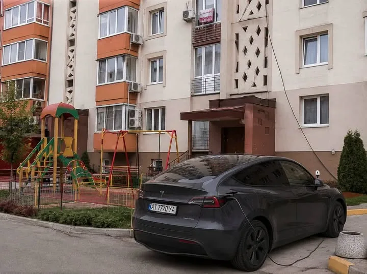 Електромобіль заряджається біля житлового будинку