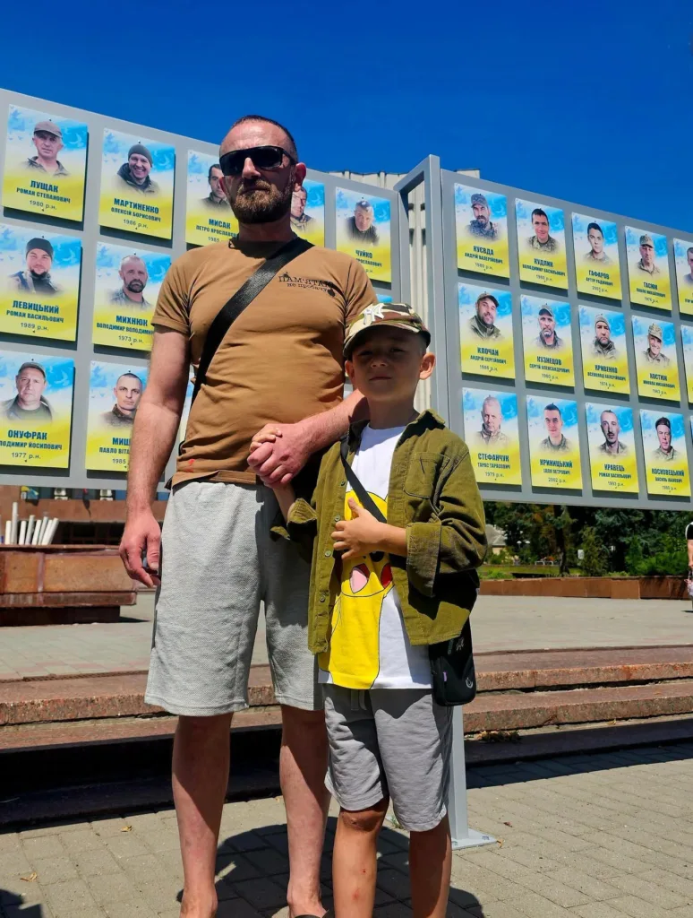 Чоловік і хлопчик біля меморіальної стіни героїв