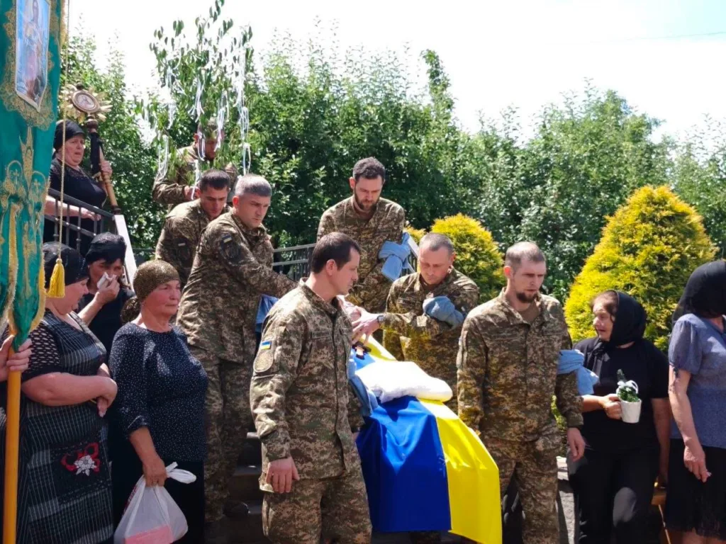 Військові несуть труну, накриту українським прапором