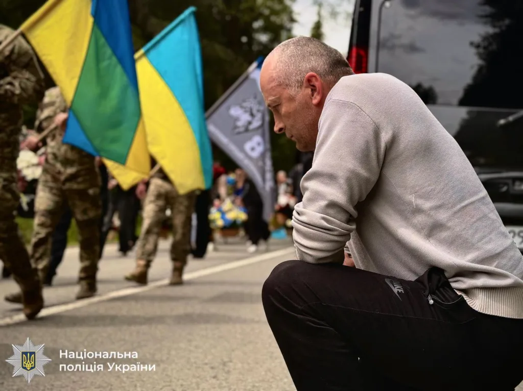 Чоловік вшановує військових із прапорами України