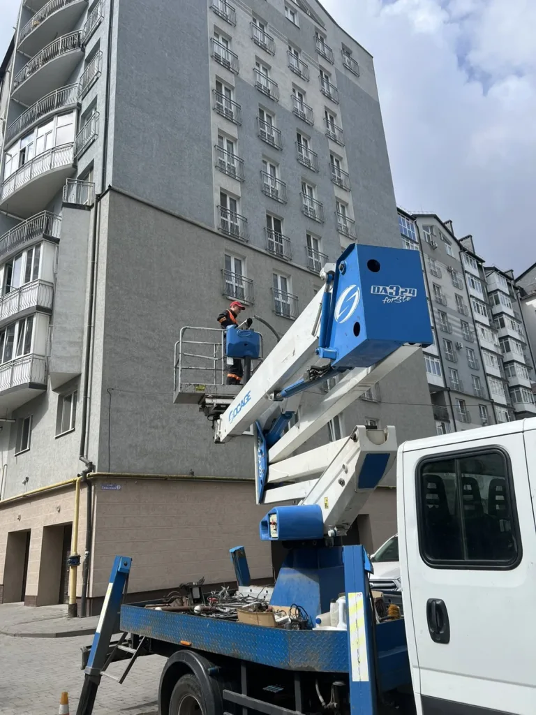Робітник на підйомнику біля багатоповерхового будинку