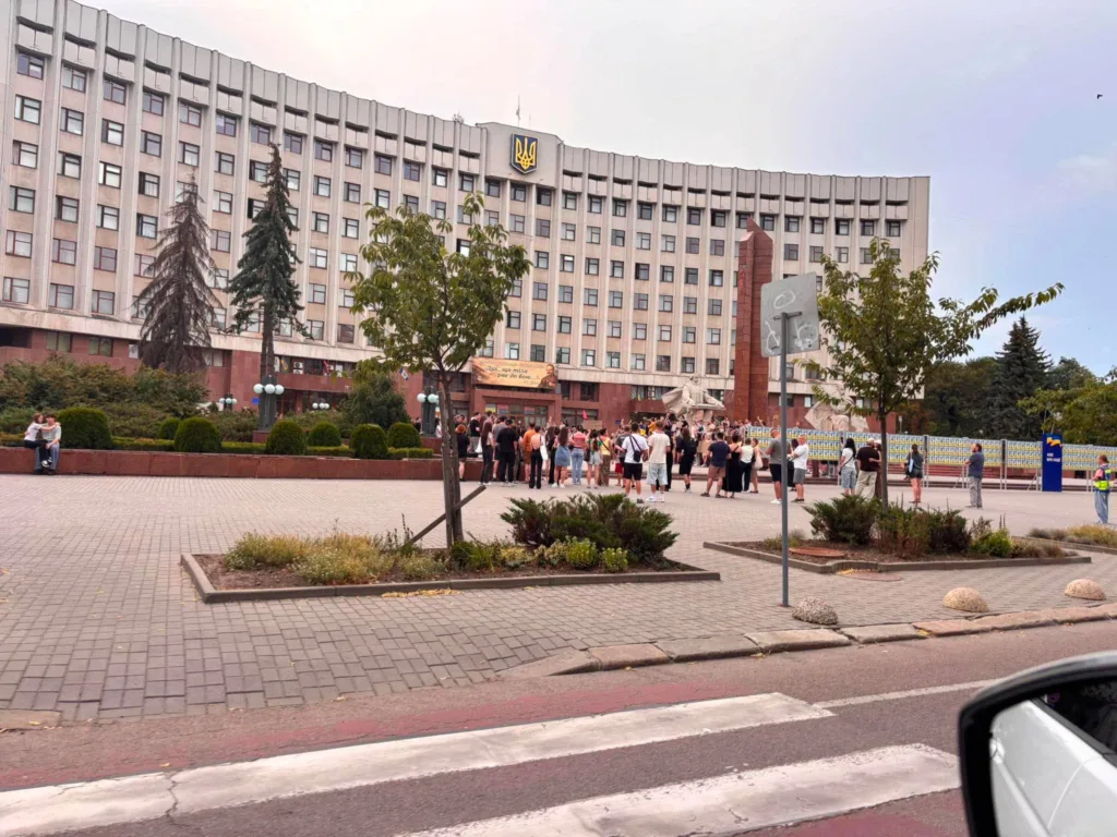 Люди перед адмінбудівлею з гербом України