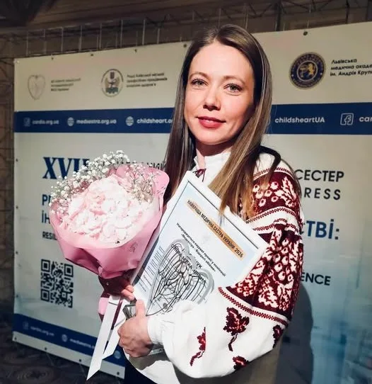 Жінка у вишиванці тримає квіти та сертифікат