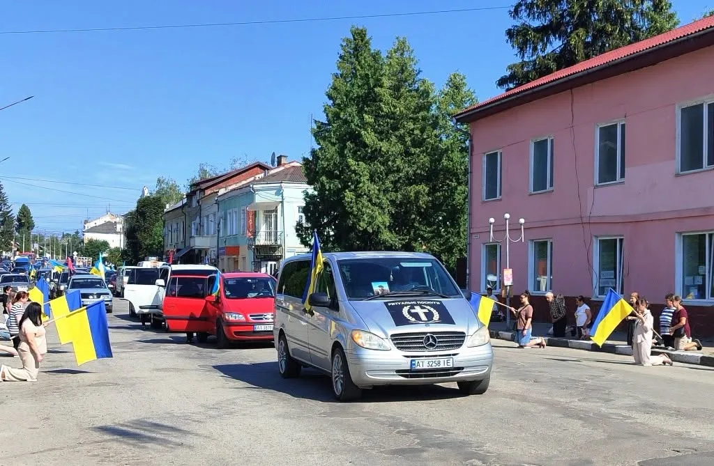 Люди з українськими прапорами на вулиці міста