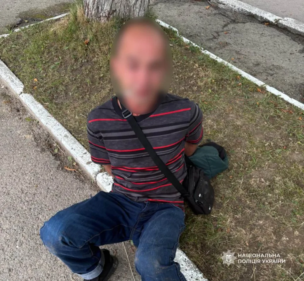 Затриманий чоловік сидить на узбіччі тротуару