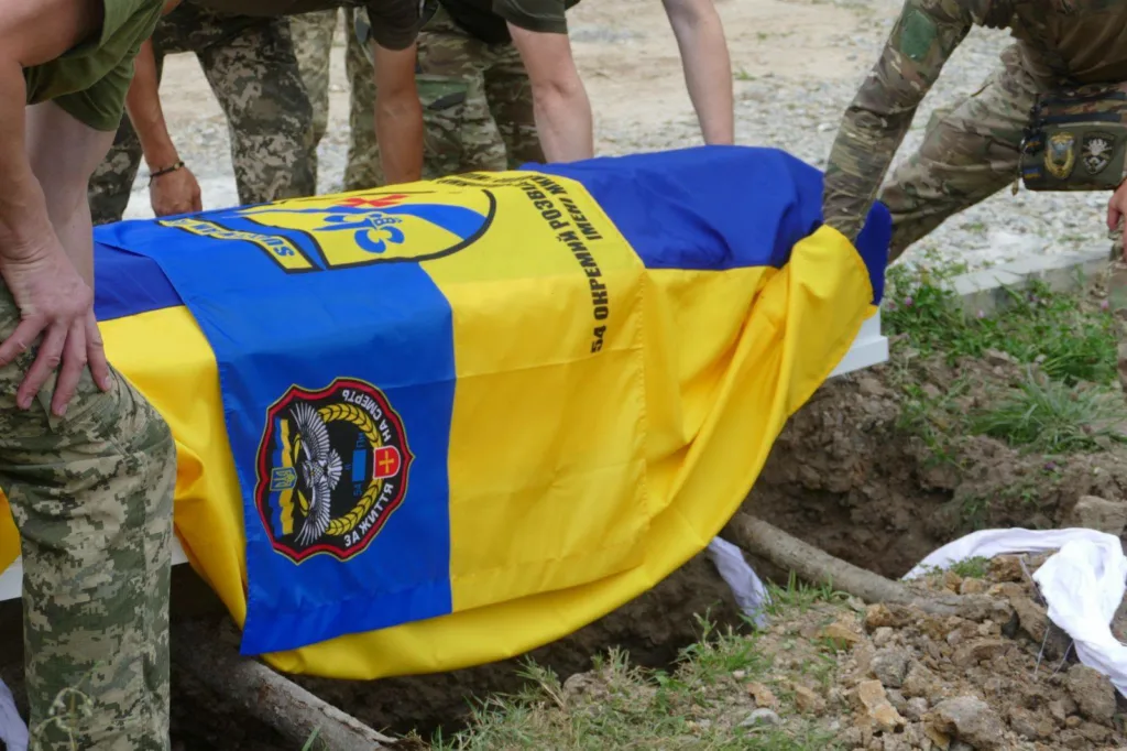 Військові ховають труну під прапором України