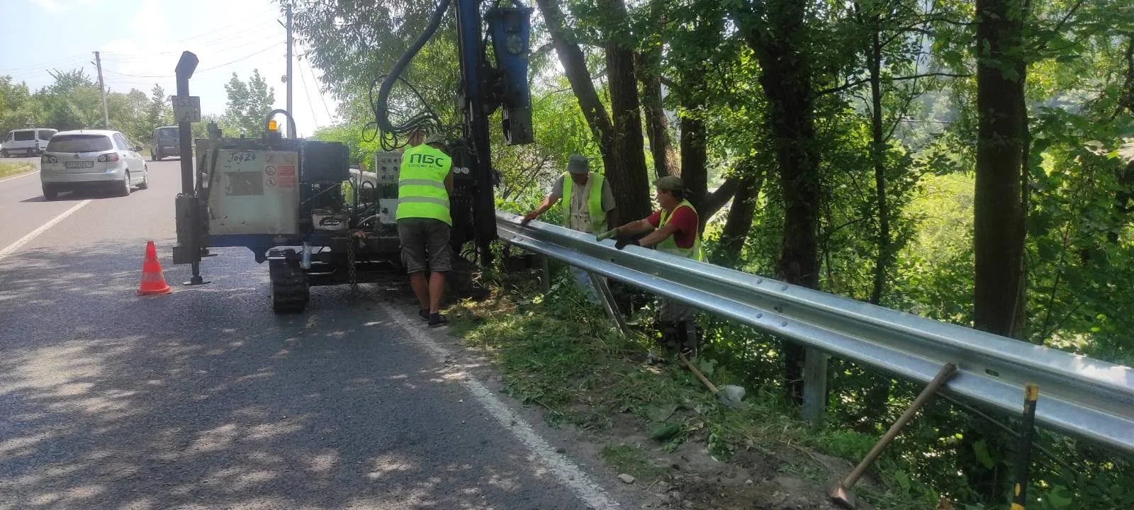 Робітники встановлюють дорожнє огородження біля лісу