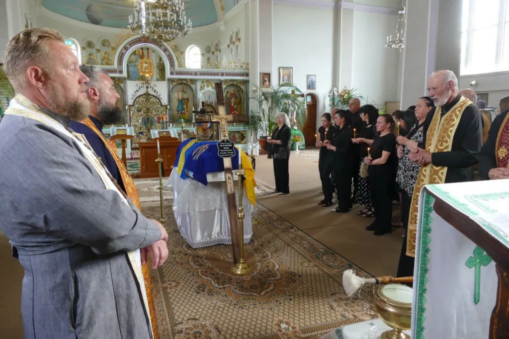 Прощання у церкві з українським прапором на труні