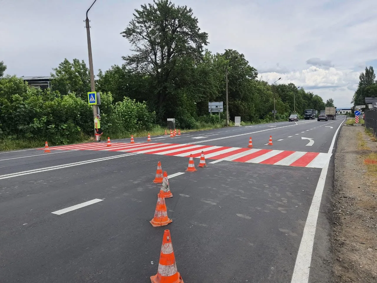 Нове пішохідне переходи з помаранчевими конусами на дорозі