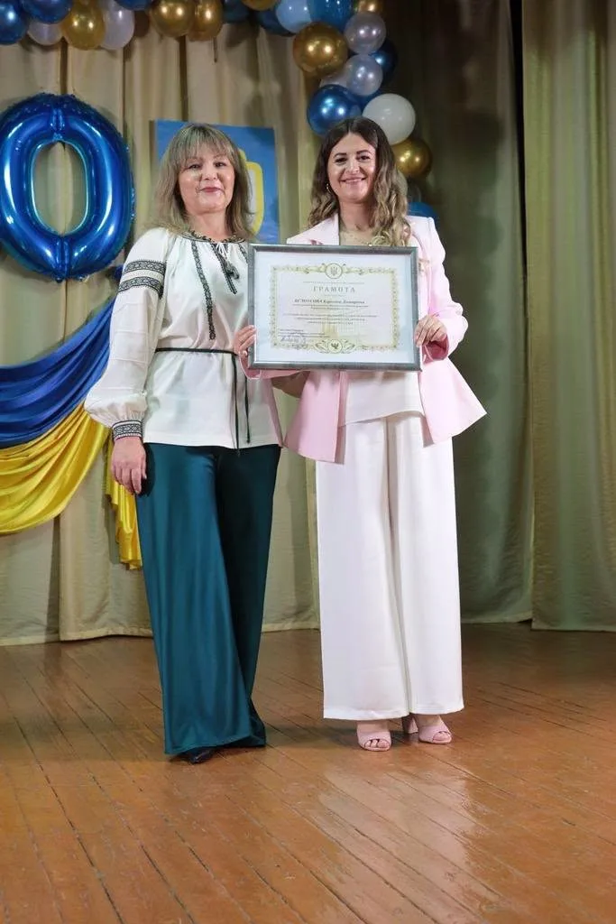 Дві жінки отримують грамоту на сцені.