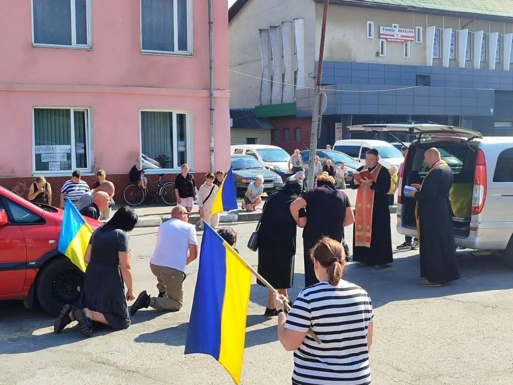 Люди моляться на вулиці з українськими прапорами
