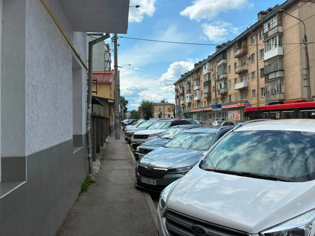 Вузький тротуар із припаркованими автомобілями в місті