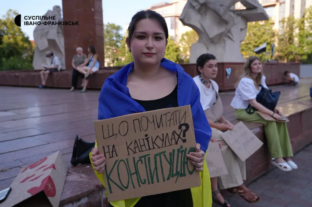 Протестувальниця з плакатом і прапором України