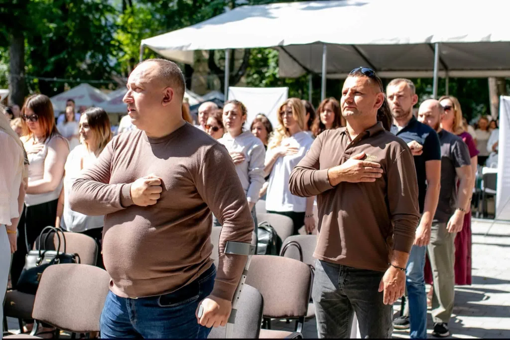 Люди стоять з рукою на серці під час церемонії