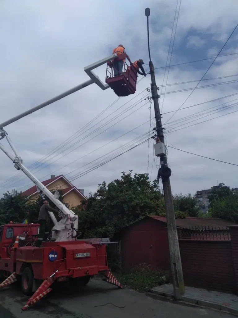 Робітники ремонтують ліхтар на електричному стовпі