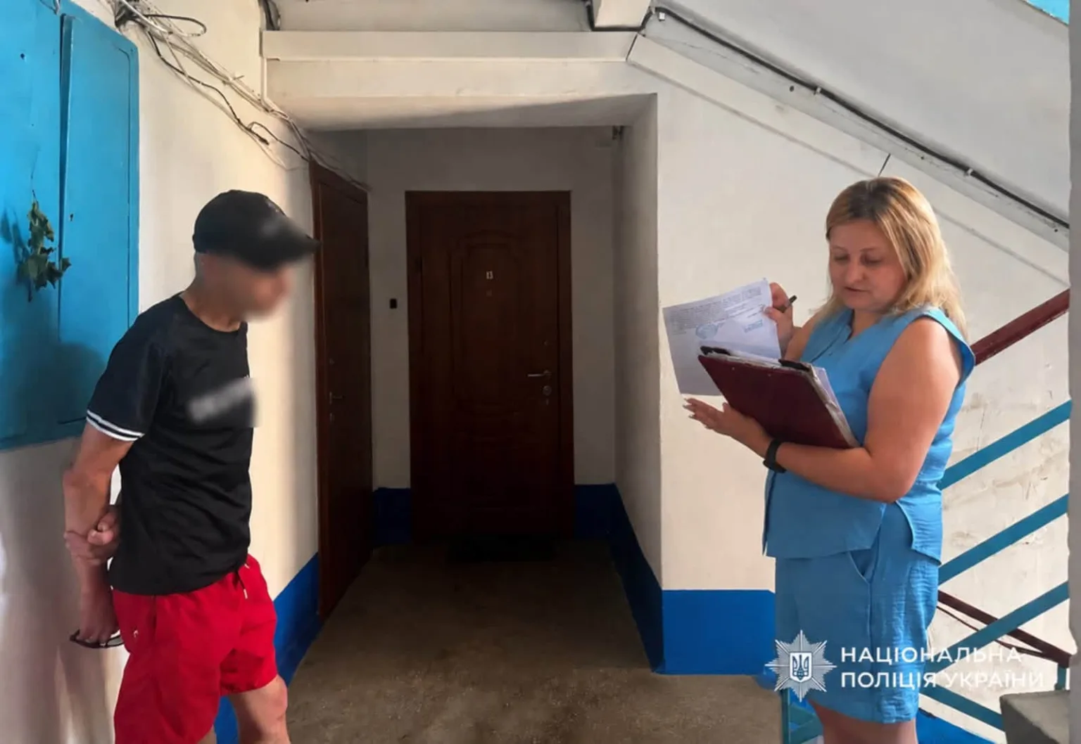 Поліцейська проводить опитування чоловіка у під'їзді