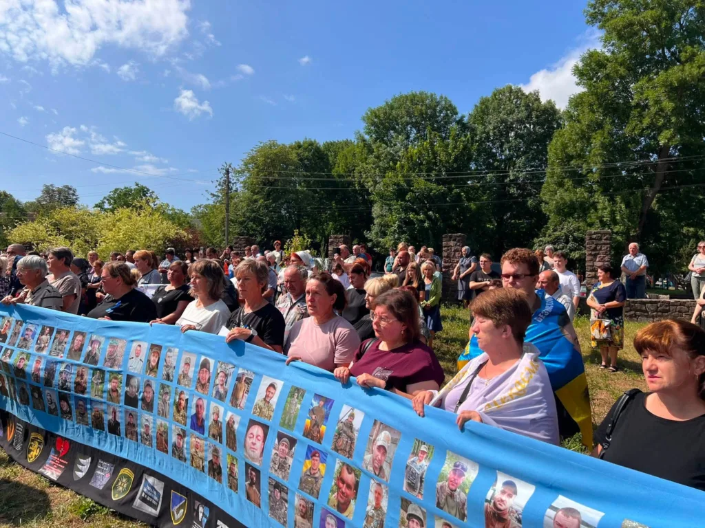 Люди тримають банер із фотографіями загиблих військових