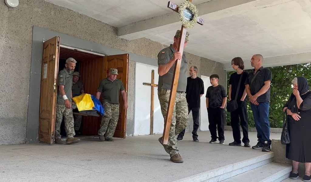 Військові несуть труну, накриту українським прапором