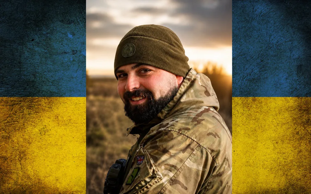 Український військовий усміхається на тлі прапора