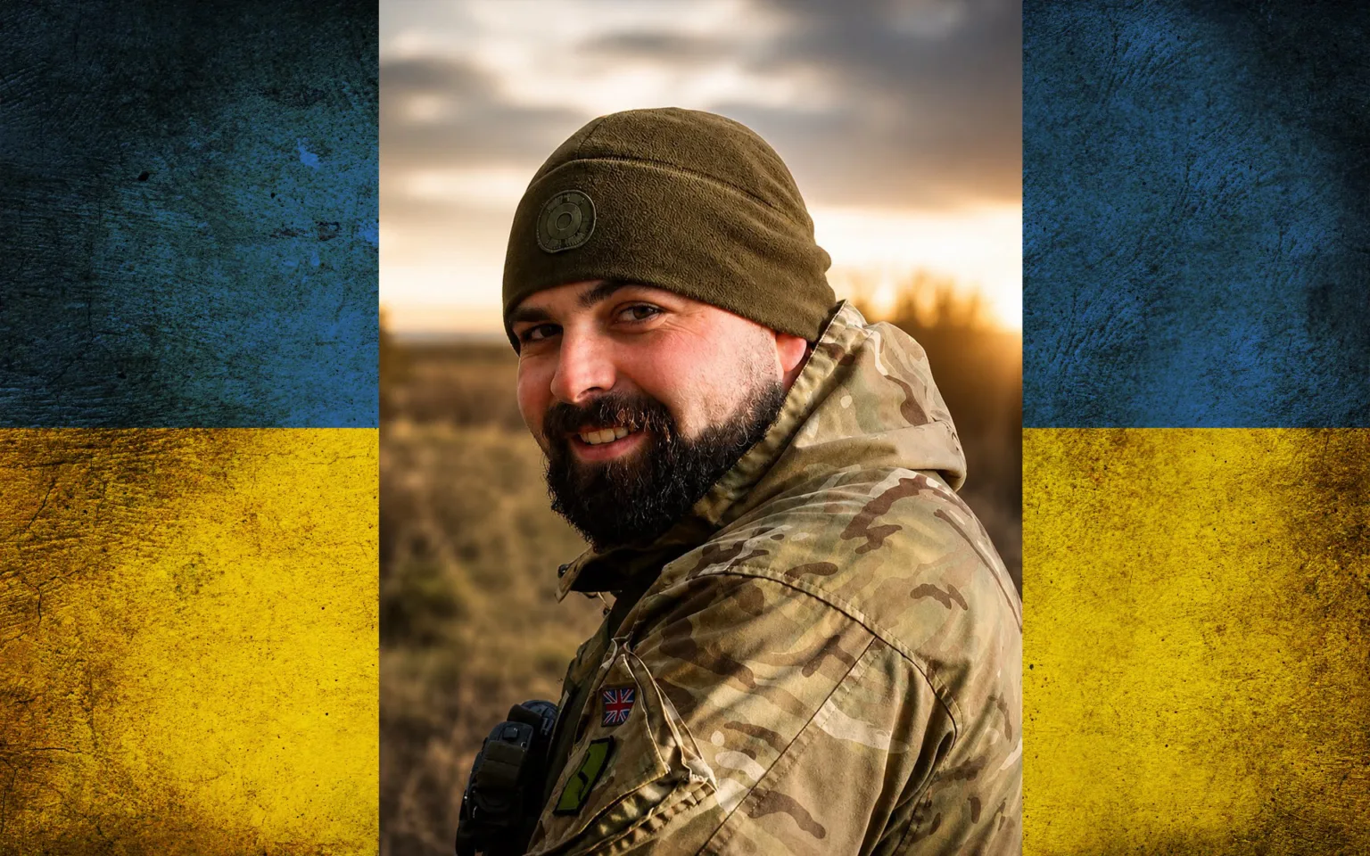 Український військовий усміхається на тлі прапора
