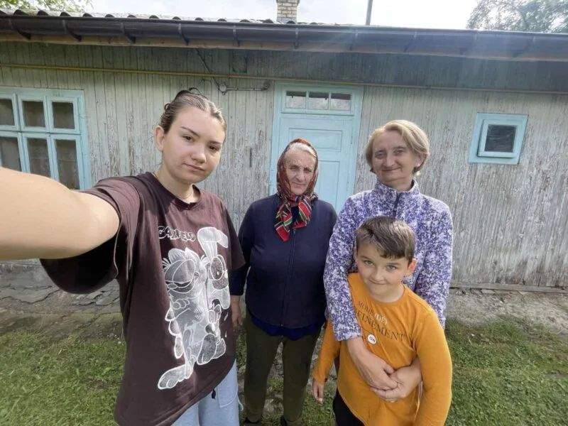 Сім'я позує перед старим дерев'яним будинком