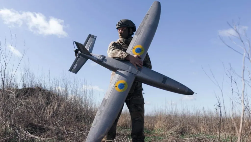 Військовий тримає безпілотник у полі