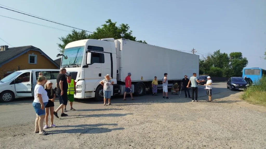 Люди біля великої білої вантажівки на дорозі