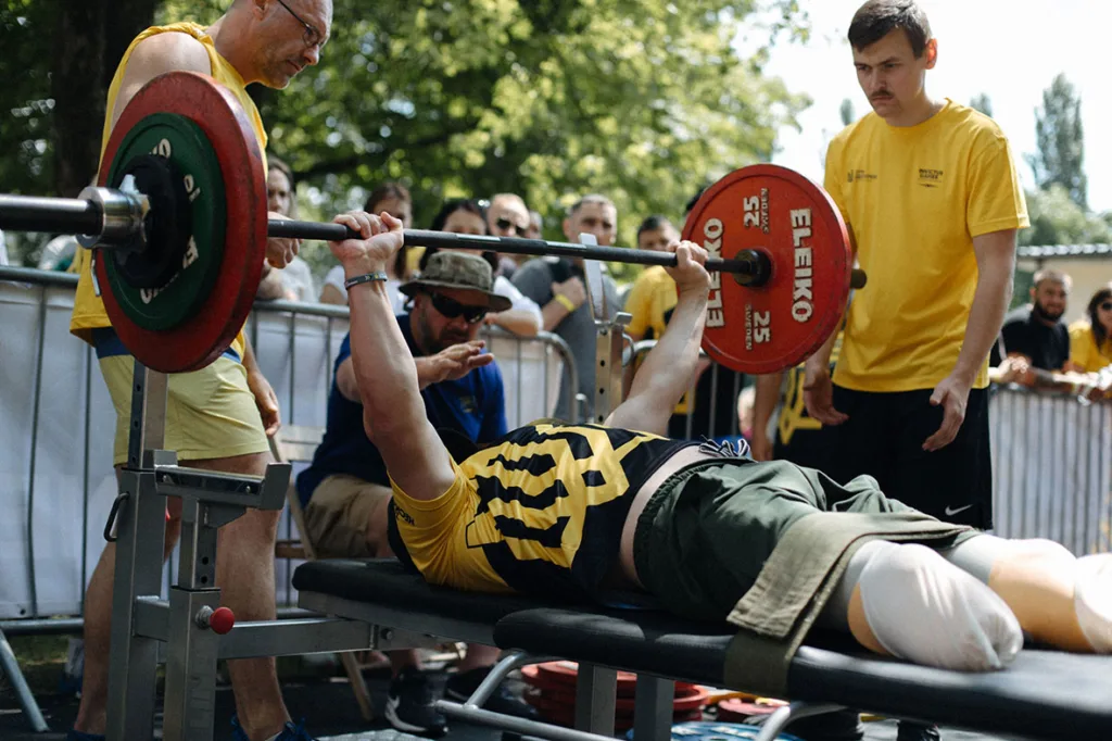 Спортсмен підіймає штангу на змаганнях просто неба
