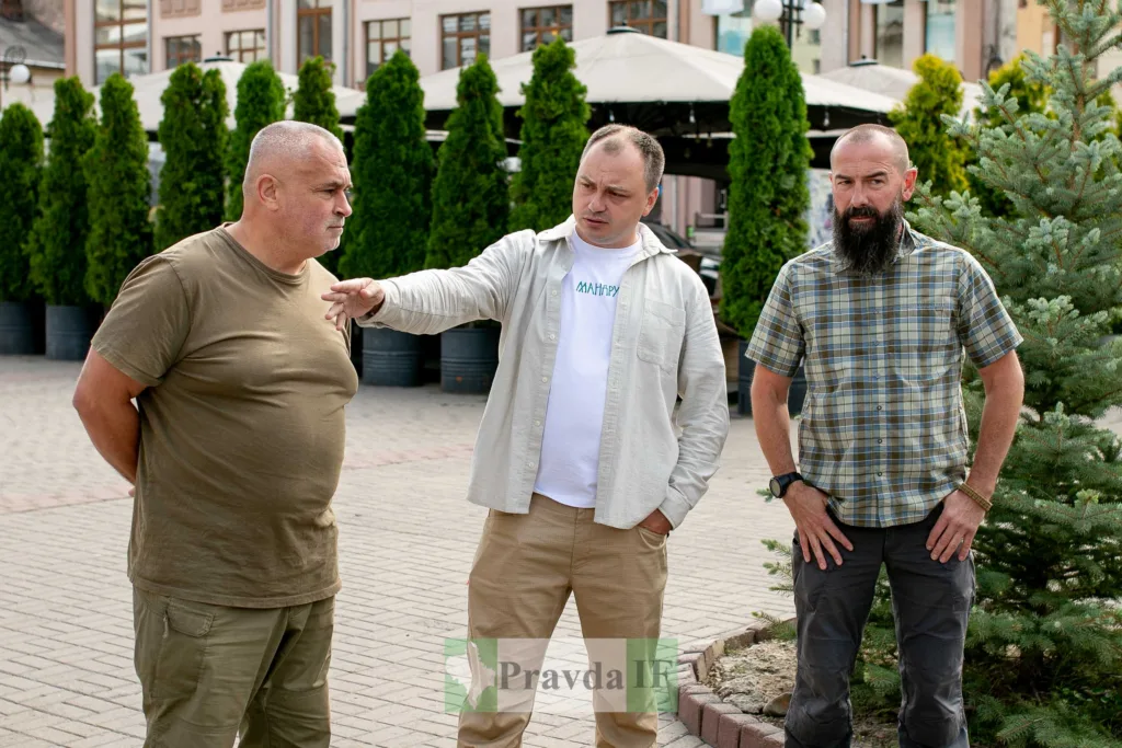 Троє чоловіків розмовляють на вулиці біля дерев