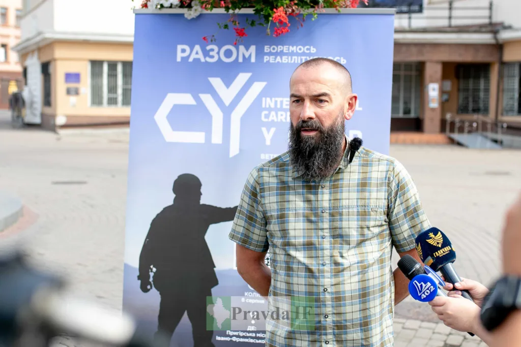 Чоловік дає інтерв'ю біля банера події
