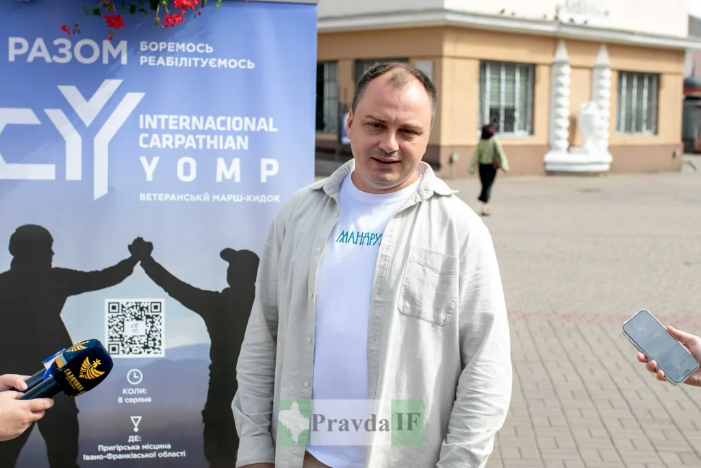 Чоловік дає інтерв’ю біля банера ветеранського маршу
