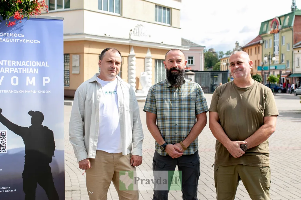 Троє чоловіків на вулиці перед банером події