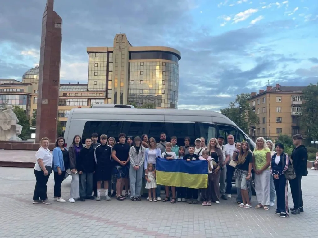 Група людей тримає прапор України біля автобуса