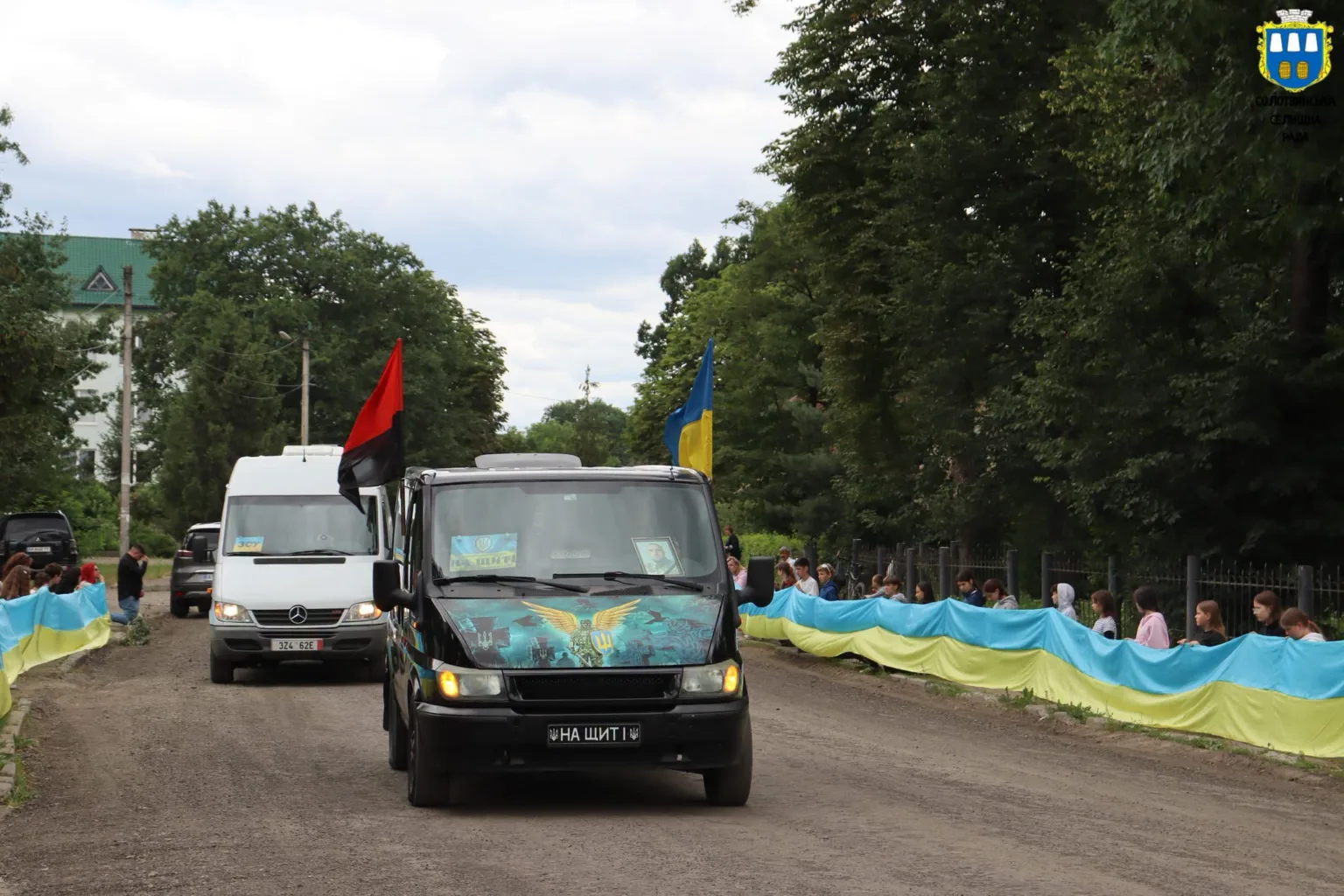 Автоколона з українськими прапорами на сільській дорозі