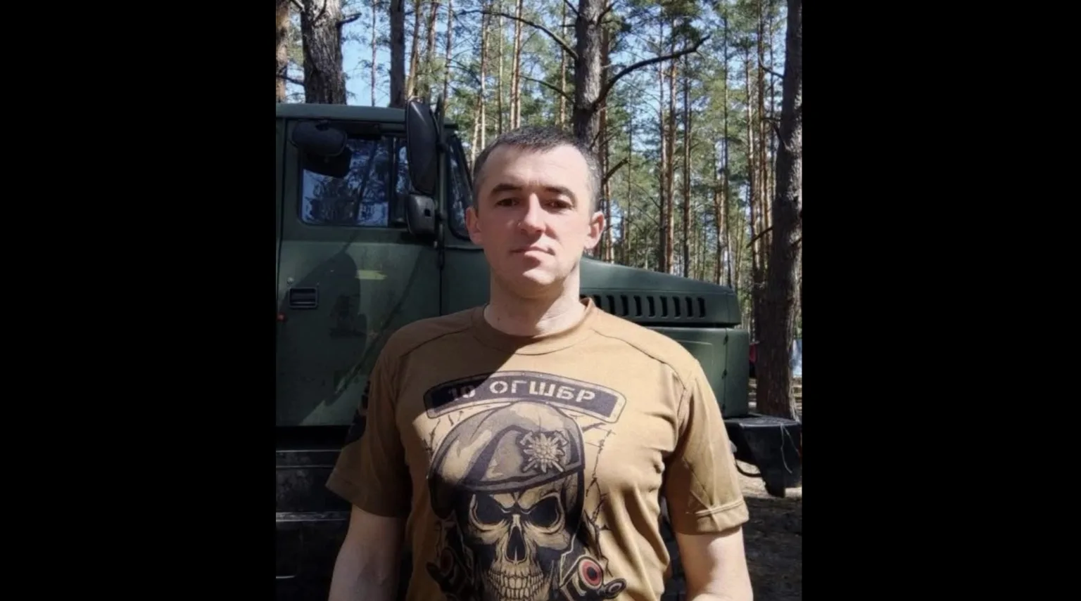Чоловік у лісі перед військовою вантажівкою