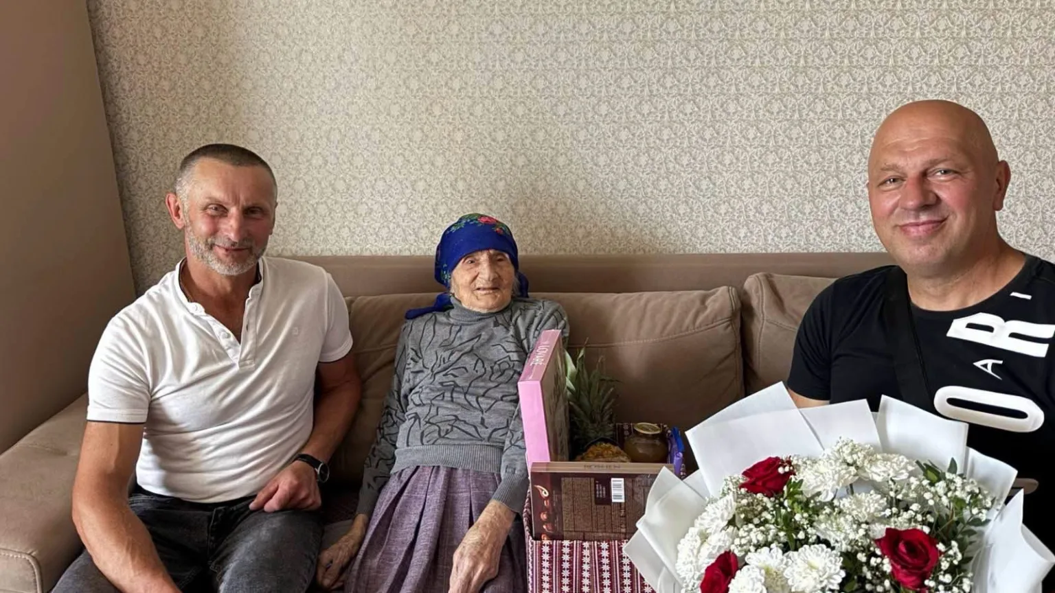 Двоє чоловіків і літня жінка сидять на дивані