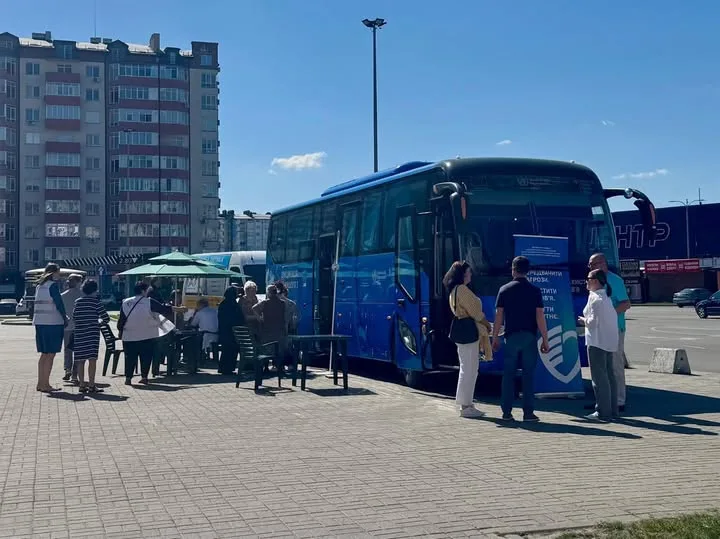 Люди біля синього автобуса на міській площі