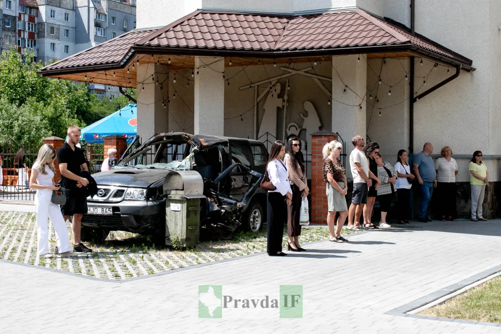 Пошкоджене авто біля будівлі, люди поруч