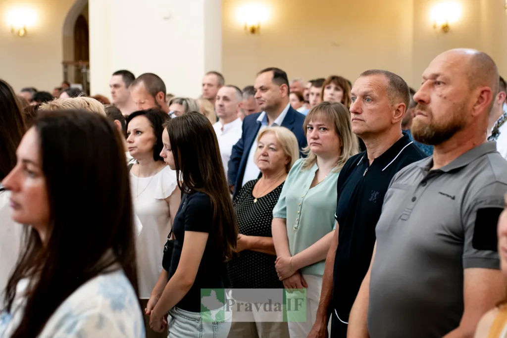 Люди стоять на урочистому заході в приміщенні