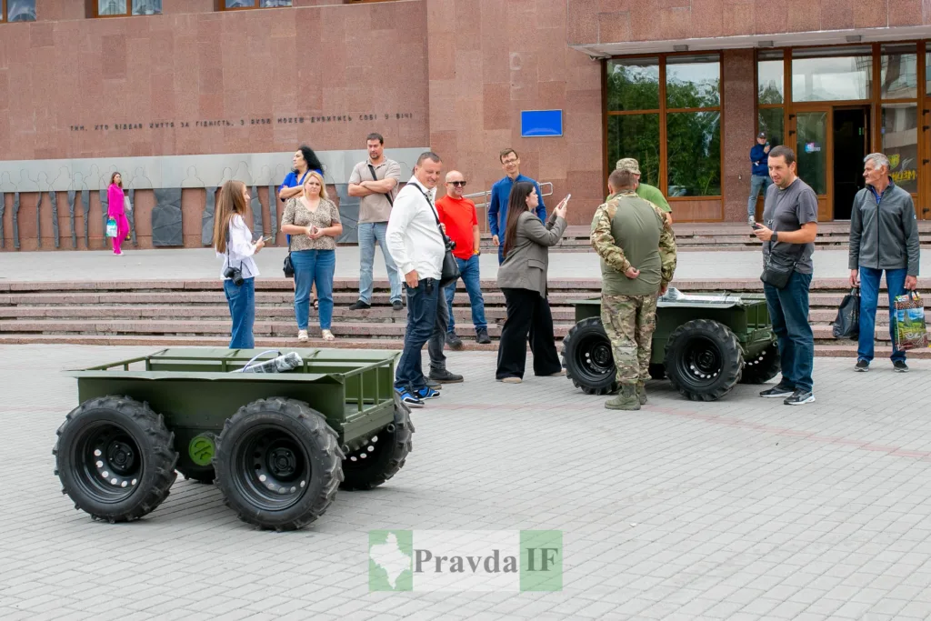 Люди оглядають військову техніку перед будівлею