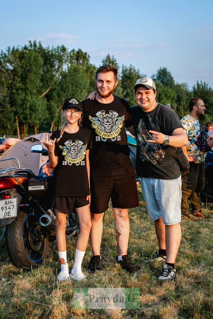 Троє людей на байкфесті біля мотоцикла